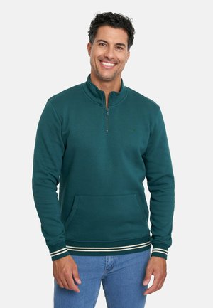 Sudadera de color verde azulado oscuro con cuello de media cremallera, bolsillo frontal y puños de canalé a rayas blancas. Tejido suave con un branding mínimo.