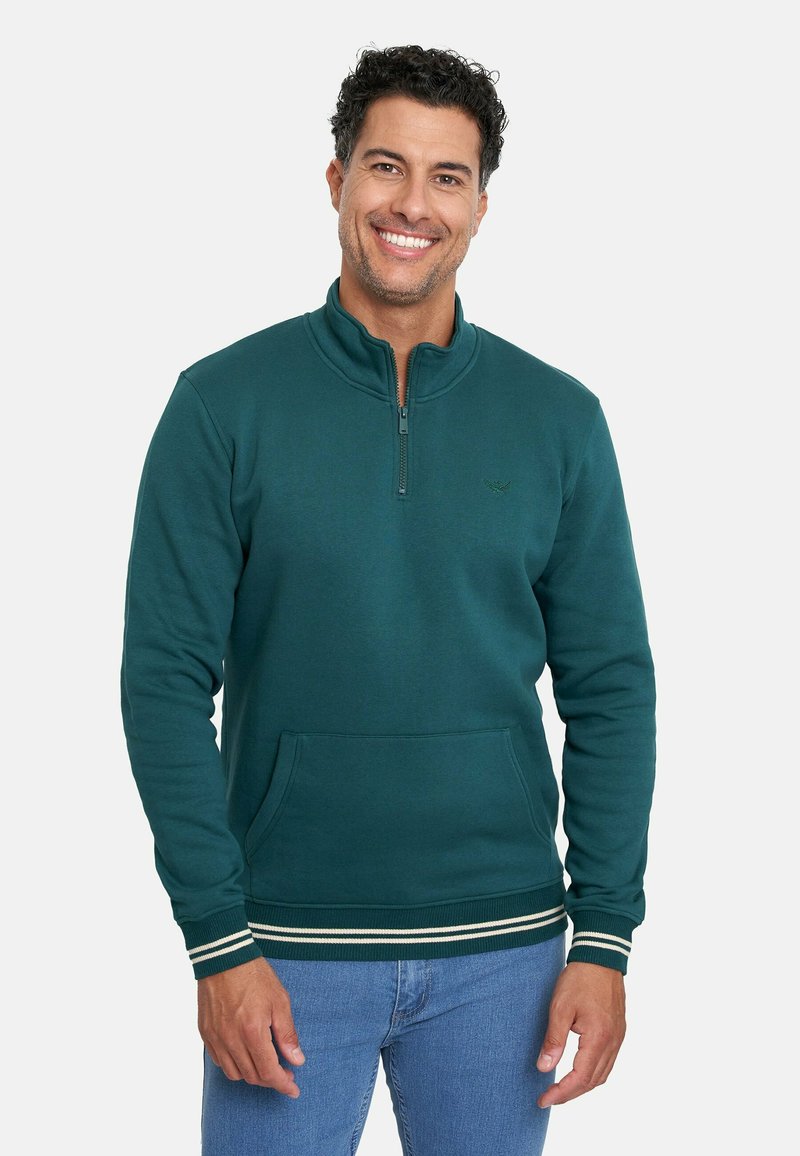 Sudadera de color verde azulado oscuro con cuello de media cremallera, bolsillo frontal y puños de canalé a rayas blancas. Tejido suave con un branding mínimo.