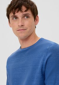 Téglakék crew-neck pulóver, textúrált anyagból készült, sima felületű, hosszú ujjú, egyszerű és laza dizájnnal.