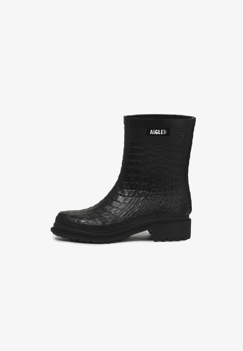 Botte en caoutchouc noire mi-mollet avec motif crocodile texturé, semelle épaisse, petit talon, et étiquette blanche "AIGLE 1853" près du sommet.