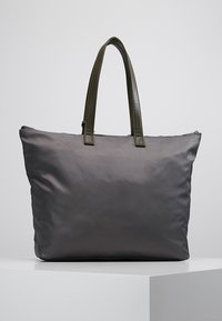 Szara torba na ramię z nylonu z dwoma zielonymi skórzanymi uchwytami, zamkiem błyskawicznym i gładką, matową fakturą. Prosty design bez widocznych wzorów i metalowych elementów.