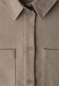 Beige Hemd zum Knöpfen mit einem Kragen, zwei Brusttaschen und strukturierter Stoff. Mit vier Knöpfen in passender Farbe.