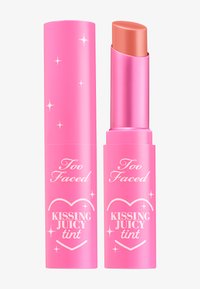 Lip tint in een roze cilindrische verpakking met een glanzend deksel, voorzien van witte tekst en steraccenten. De kleur van de tint is een zachte perziktoon.