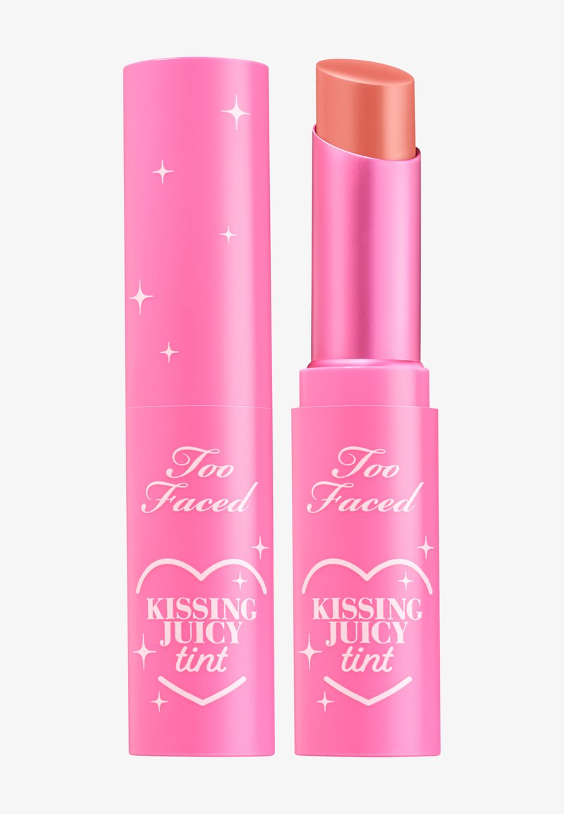 Lip tint in een roze cilindrische verpakking met een glanzend deksel, voorzien van witte tekst en steraccenten. De kleur van de tint is een zachte perziktoon.