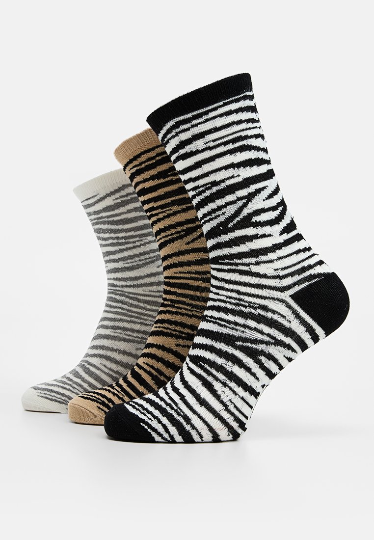 Tres pares de calcetines de tripulación presentan un diseño de rayas de cebra en colores negro, beige y gris, hechos de un material de punto suave y elástico.