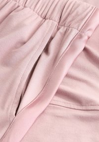 Tessuto rosa chiaro con una morbida trama, dotato di una vita elasticizzata e pieghe sottili, evidenziando un design liscio e traspirante.