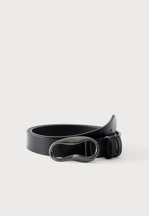 Zwarte leren riem opgerold met een gladde, glanzende, onregelmatig ovale zwarte metalen gesp op een effen witte achtergrond.