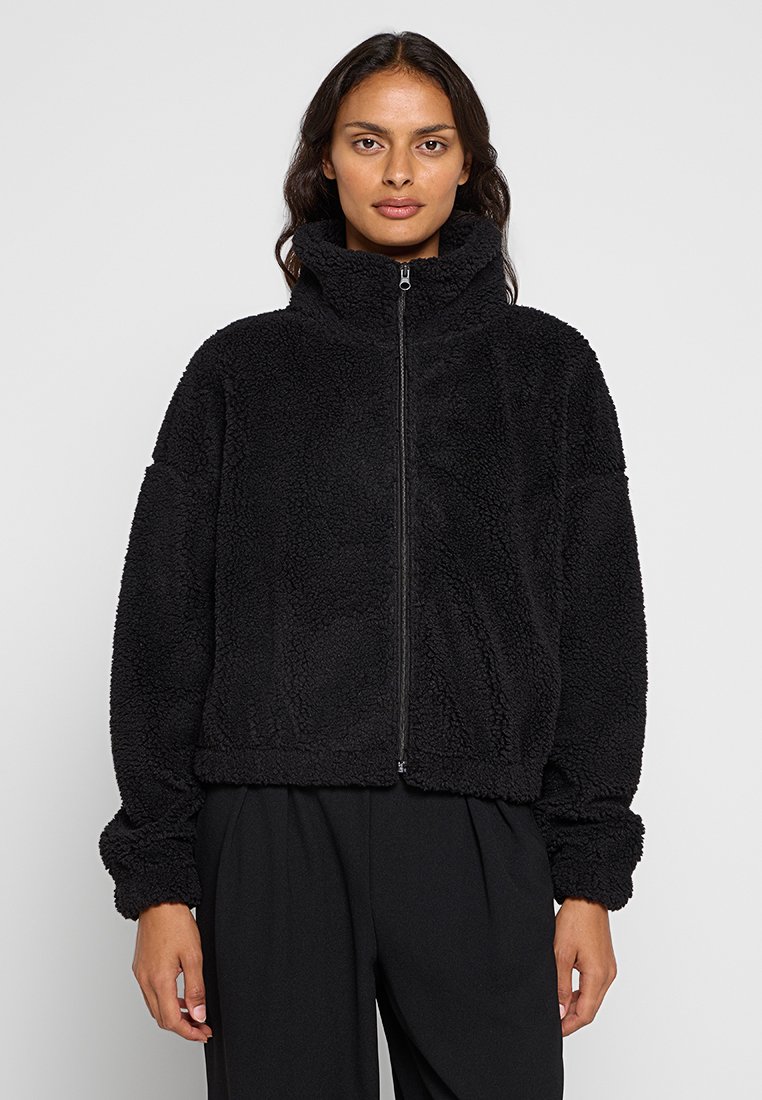Schwarze Fleece-Jacke mit hohem Kragen, Reißverschluss und lässiger Passform. Besitzt ein weiches, strukturiertes Material und lange Ärmel, ideal für Wärme.