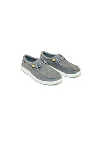 Zapatos de ante gris con una suela de goma blanca, diseño sin cordones y acentos decorativos en tono marrón con un detalle metálico.