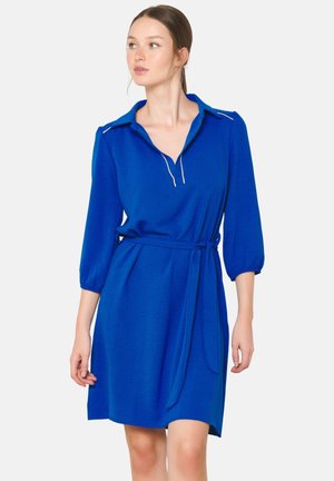 Robe bleue avec des manches trois-quarts, un col et une ceinture à nouer à la taille. Présente une texture lisse et des détails brodés subtils.