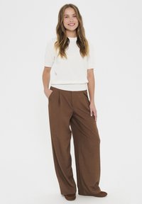 White short-sleeve top paired with high-waisted brown wide-leg trousers. Fabric appears smooth and textured, with pleats at the front.