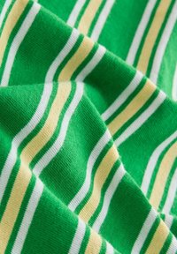 Tissu vert avec des rayures horizontales blanches et jaune clair, montrant des plis doux et une texture tricotée.