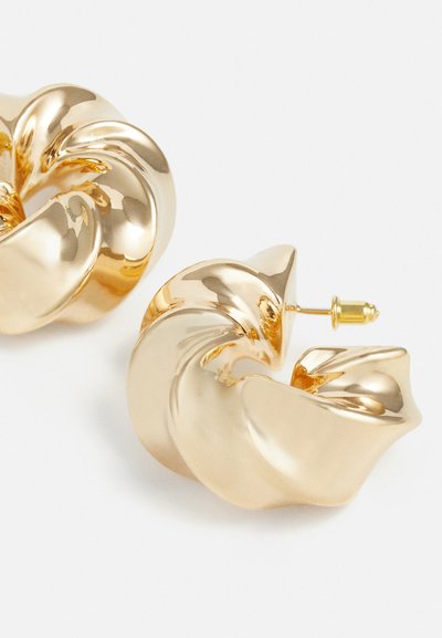 Gold-tone metal earrings with a twisted, spiral design. Smooth, reflective surface with a polished finish and a push-back fastening.