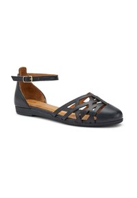 Zapato plano de cuero negro con diseño abierto de tiras cruzadas en la puntera, correa en el tobillo con hebilla y suela plana. Textura suave y estilo casual.