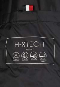 Must värvi kangas valge tekstiga H-XTECH Protect omadustega: veekindel, hingav, tuulekindel, peamise õmblused teibitud. Punased, valged ja sinised aktsendid.