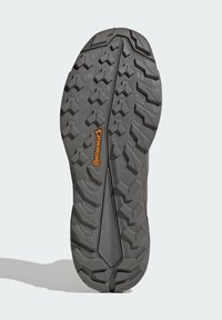 Grå gummisula på sneakers med ett texturerat mönster av sexkantiga och triangulära former; "Continental"-logotyp i orange.