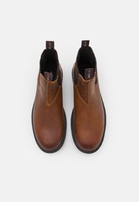 Bottines en cuir marron avec panneaux latéraux élastiques, bout rond et semelle en caoutchouc noir contrastant. Vue de dessus mettant en valeur les détails de couture.