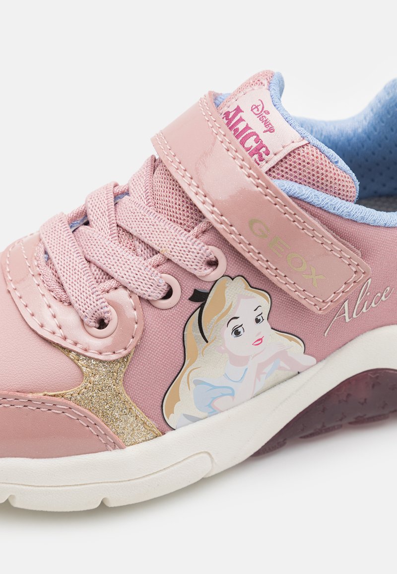 Sneaker rose avec une bande Velcro, une languette en mesh, un accent en paillettes dorées et une illustration d'un personnage. Texture douce et semelle en caoutchouc.