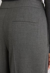 Sive krojene hlače s teksturiranom tkaninom. Imaju jednu stražnju džep i ravni pojas, dizajnirane za uski siluetu.