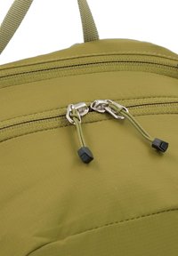 Primer plano de una mochila verde oliva que presenta dos cierres de cremallera con topes de plástico negro y una superficie de tela texturizada.