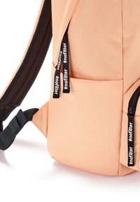 Zaino color pesco realizzato in tessuto liscio, dotato di spallacci in rete nera, tasche con zip e tirazip brandizzati con il testo "#nofilter".