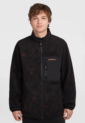 Junger Mann trägt eine schwarze Fleece-Jacke mit Reißverschluss, Brusttasche und O'Neill-Logo auf der linken Seite.