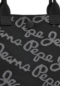 Zwarte stoffen boodschappentas met een herhalend grijs schriftpatroon. Voorzien van stevige handvatten en een zwarte drukknoopsluiting. Textuur materiaal.
