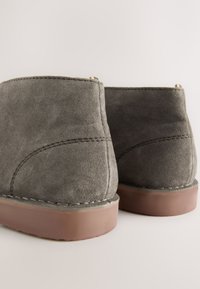 Grau Veloursleder Stiefeletten mit glatter, weicher Textur; braune Gummisohlen; minimalistische Nähte; und ein flaches, unauffälliges Design.