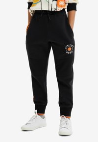 Zwarte sweatpants met mesh panelen, geribde boorden, een trekkoord in de taille en een 'Basketball Hero' grafiek; ver accented met oranje details.