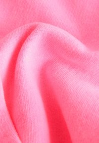 Minkštos rožinės spalvos megzta medžiaga su smulkia tekstūra ir švelniais raukšlėmis, kurios kuria subtilias šešėlių ir šviesos žaismą.