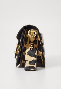 Leren portemonnee met een luipaardprint in goud en zwart, met een sleutelhanger en een kleine leren tag eraan bevestigd.