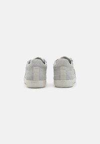 Sneaker in suede grigio con finitura texture, caratterizzate da una suola in gomma bianca e un design semplice. Il tallone presenta un accento verticale.