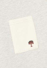Hellgrauer Stoff mit einer weißen Tasche, die einen gestickten grünen Baum mit roten Früchten zeigt. Glatte Textur, einfaches Design, keine zusätzlichen Muster.
