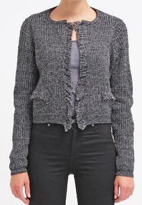 Gray textured cardigan with a round neck, frayed edges, and open front. Worn over a gray top with black fitted pants.