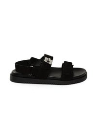 Svart sandal med två justerbara remmar, en slät textur, en gummisula och en metallisk detalj på sidan.