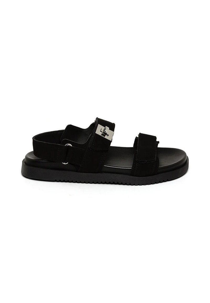 Svart sandal med två justerbara remmar, en slät textur, en gummisula och en metallisk detalj på sidan.