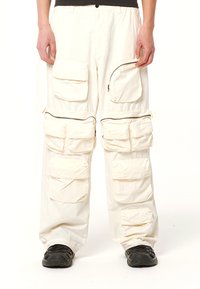 Cargo-Hosen aus leichtem Stoff, in Weiß, mit mehreren vorderen Taschen und einem mit einem Reißverschluss versehenen Fach am Oberschenkel.