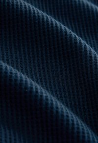 Tela de color azul marino con textura y patrón acanalado. El material parece suave y ligeramente elástico, mostrando un color profundo y finos detalles.