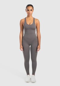 Grå atletisk jumpsuit med rund halsudskæring og brede stropper, der har en tætsiddende pasform. Materialet ser glat og strækbart ud, hvilket gør det ideelt til aktivt tøj.