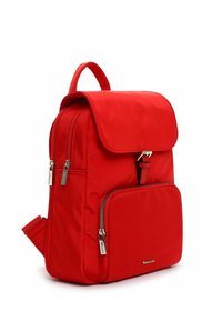 Mochila de nylon roja con cierre de solapa, asa superior, bolsillo lateral con cremallera y detalles en hardware plateado. Textura suave y diseño compacto.
