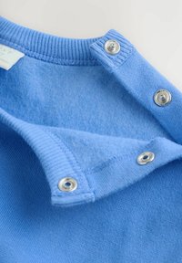 Svetlo modra jopa z rebrastim ovratnikom, s pritiskači in mehko notranjo podlogo. Ima gladko teksturo in priložnostni dizajn.