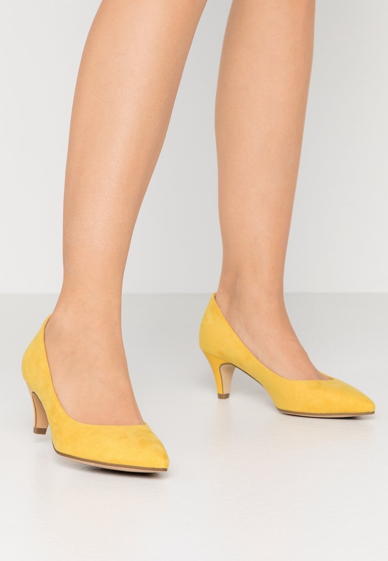 Chaussures à talons hauts en daim jaune, à bout pointu, avec une texture lisse et un talon fin et effilé. Design simple sans ornements.