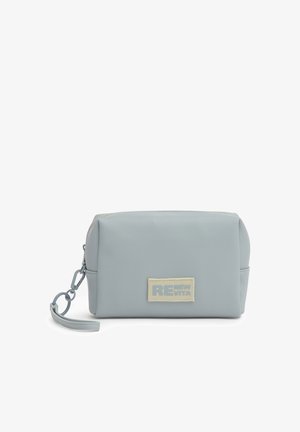Bustina rettangolare azzurro chiaro con cerniera e cinturino da polso, con etichetta beige con testo parzialmente visibile.