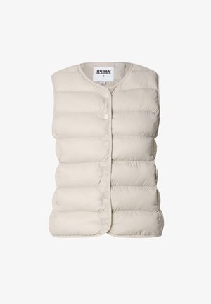 Világos bézs színű pufidakota, kerek nyakkivágással, patentos gombokkal az elején és steppelt mintával az anyagon.