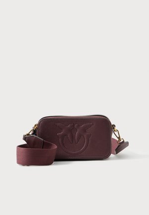 Bordeaux læder crossbody taske med præget logo, lynlåslukning og aftagelig stofrem. Tekstureret overflade og kompakt rektangulær form.