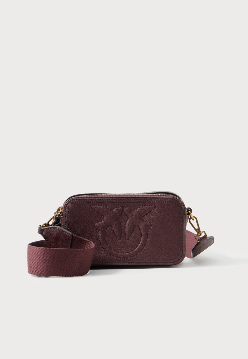 Burgundská kožená crossbody taška s embosovaným logem, zipovým uzávěrem a odnímatelným textilním popruhem. Texturovaný povrch a kompaktní obdélníkový tvar.