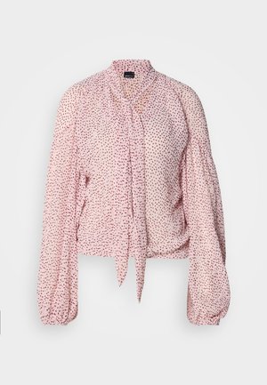 Palaidinė iš šviesiai rožinės medžiagos, išmarginta raudonomis dėmėmis; turi kaklo raištelį ir pūstus ilgus rankovės. Tekstūruota, minkšta medžiaga.