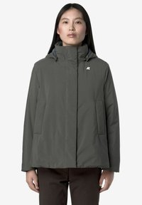 Veste à capuche gris foncé avec une finition lisse et texturée, comportant deux poches avant et un petit logo sur le côté gauche de la poitrine.