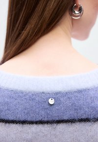 Pull en maille violet clair avec une texture douce, présentant un col bas et une étiquette argentée décorative à l'arrière. Accent rayé plus foncé en dessous.