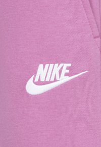 Rozā mikene audums ar mīkstu tekstūru, uz kuriem priekšā ir balts izšūts "Nike" logo.